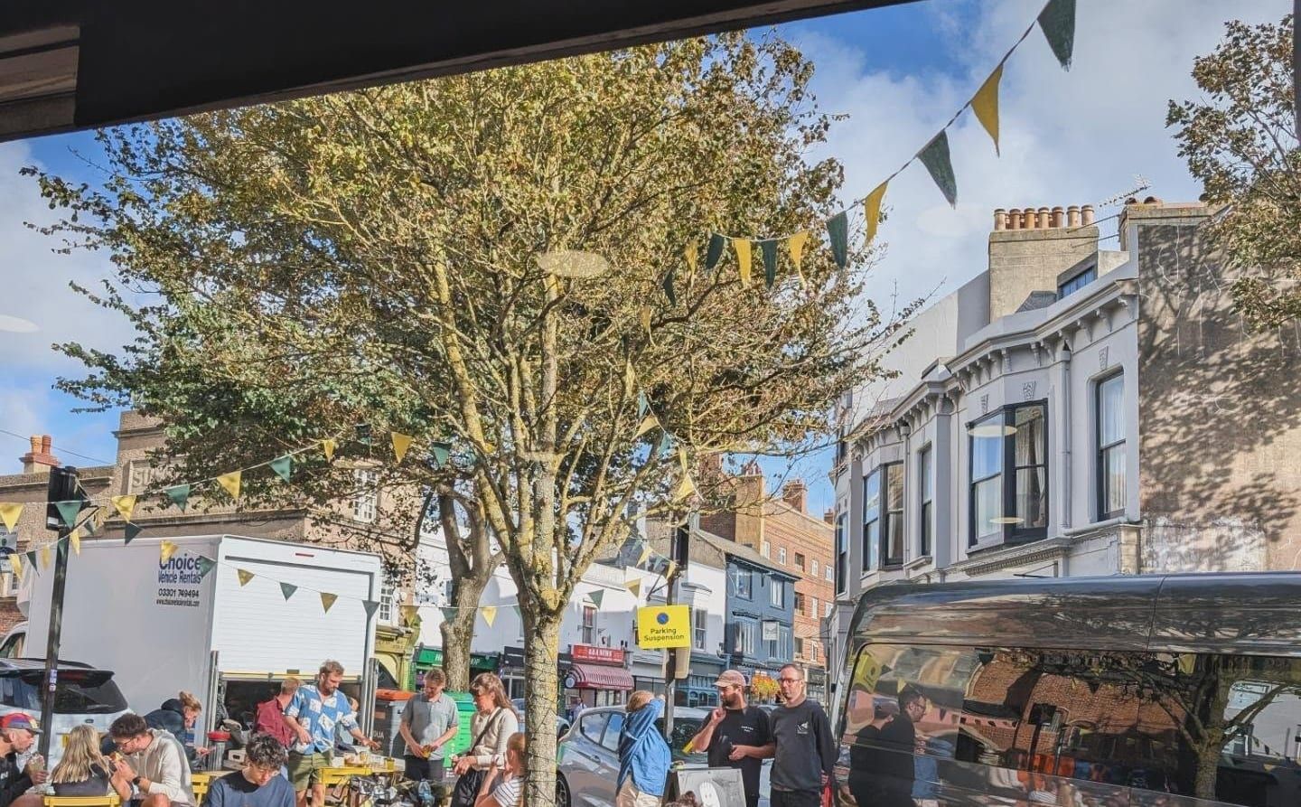 Sunny outdoor seating with yellow chairs and bunting in the pickle square outside The Pickle, Kemptown