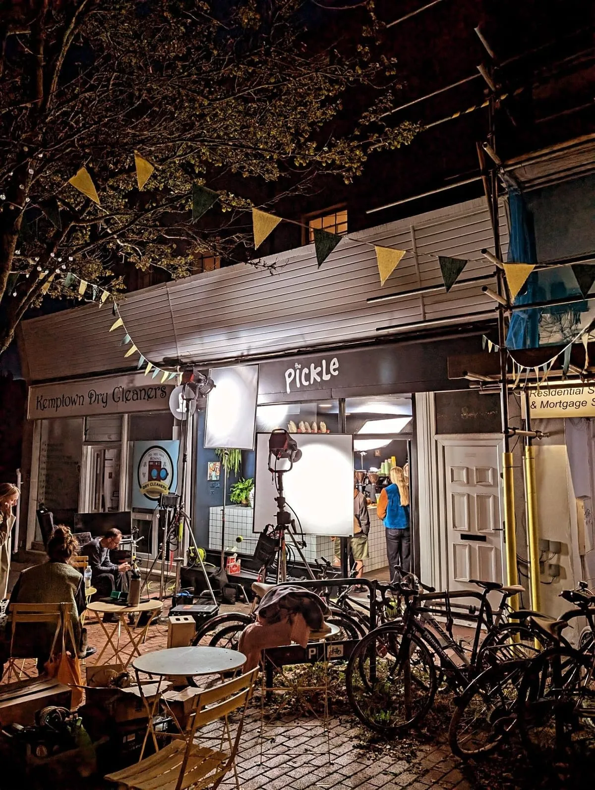The Pickle shopfront at night with bunting and bikes on Bristol Road, Kemptown